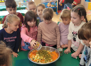 Dziewczynka dodaje kukurydzę do sałatki.