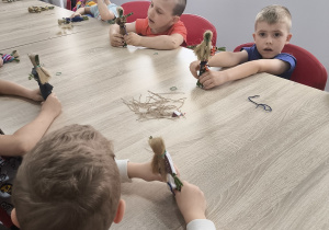 Dzieci podczas pracy nad samodzielnie wykonywaną laleczką z sitowia