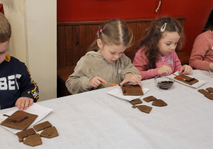 Dzieci wykonują domki z pierników.