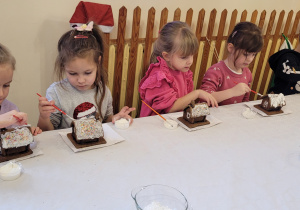 Dzieci dekorują domki z pierników.