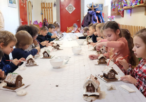 Dzieci dekorują domki z pierników.