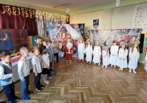 Dzieci stoją w półkolu i śpiewają utwór Czerwonych Gitar "Jest taki dzień"