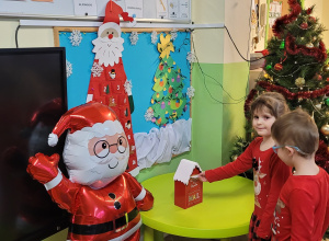 Dwoje dzieci wrzuca list do skrzynki pocztowej Świętego Mikołaja