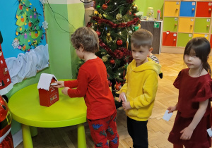 Dzieci po kolei wrzucają listy do skrzynki na listy do Świętego Mikołaja