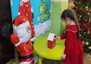 Dziewczynka ubrana na czerwono umieszcza list w skrzynce na listy