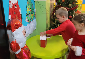 Chłopiec i dziewczynka umieszczają listy w skrzynce do Mikołaja