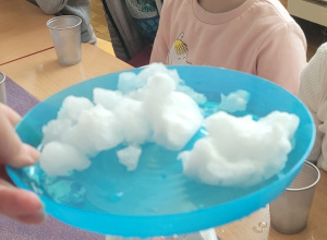 Dzieci obserwują roztapianie się śniegu pod wpływem ciepła emitowanego przez świecę.