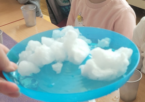 Dzieci obserwują topienie się śniegu pod wpływem ciepła.