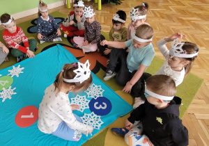 Dziecko porządkuje gwiazdki według kształtu, przelicza i przyporządkowuje do odpowiedniej cyfry.