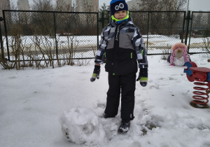 Chłopiec toczy śnieżną kulę