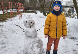Chłopiec prezentujący własnoręcznie ulepionego bałwana