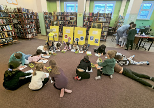 Dzieci kolorujące obrazki znaków drogowych podczas zajęć w bibliotece