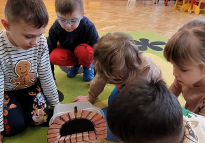 Chłopiec wkłada pizzę do papierowego pieca