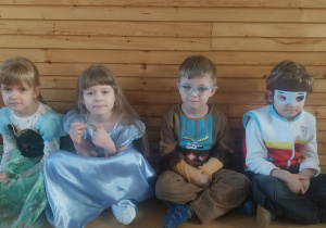 Dwie dziewczynki i dwóch chłopców w przebraniach karnawałowych odpoczywają po tańcu.