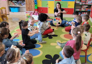 Dzieci wspólnie z nauczycielem pokazują za pomocą języka migowego kolor pomarańczowy.