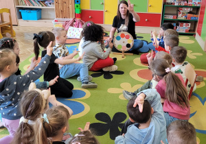 Dzieci wspólnie z nauczycielem, za pomocą języka migowego pokazują kolor niebieski.