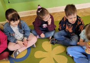 Dzieci siedząc w kręgu poznają zapach cytryny i wypowiadają się na temat jej aromatu.