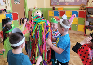 Dzieci w klasie dekorują marzannę kawałkami bibuły.