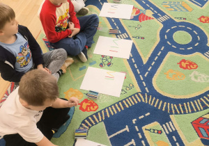 Dzieci z grupy Jagody uczą się zapisu liczb rzymskich z użyciem patyczków