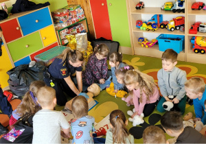 Dzieci uczą się wykonywać masaż serca, ćwicząc na maskotkach.