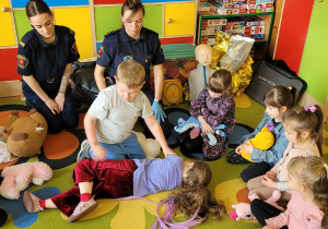 Chłopiec układa dziewczynkę w pozycji bocznej ustalonej.