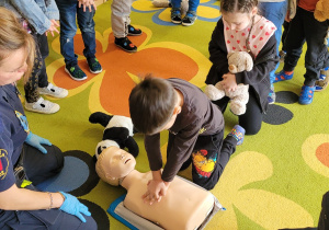 Dziewczynka wykonuje masaż serca na manekinie.