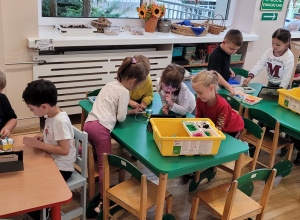 Dzieci w kilkuosobowych grupach budują roboty z klocków.