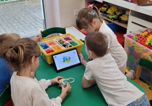 Dzieci odczytują instrukcję obrazkową na tablecie.