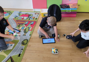 Trzech chłopców steruje zbudowanym robotem.