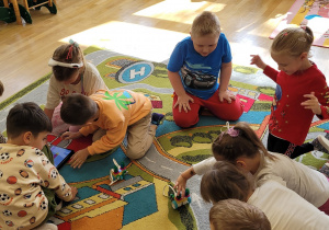 Grupka dzieci bawi się zbudowanymi przez siebie robotami.