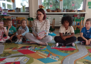 Mama jednego z dzieci, czyta wiersze Juliana Tuwima grupie dzieci w klasie.