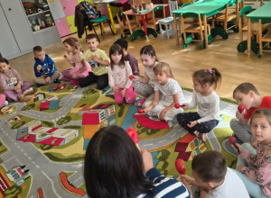 Grupa dzieci z nauczycielem gra na instrumentach perkusyjnych.