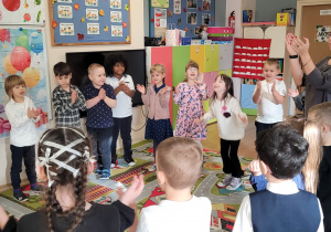 Dzieci stoją w kole i wspólnie śpiewają solenizantce.