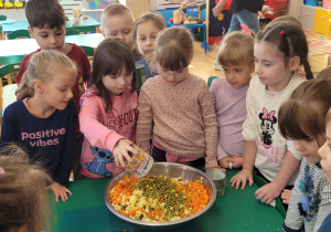 Dziewczynka wsypuje kukurydzę do miski z sałatką.